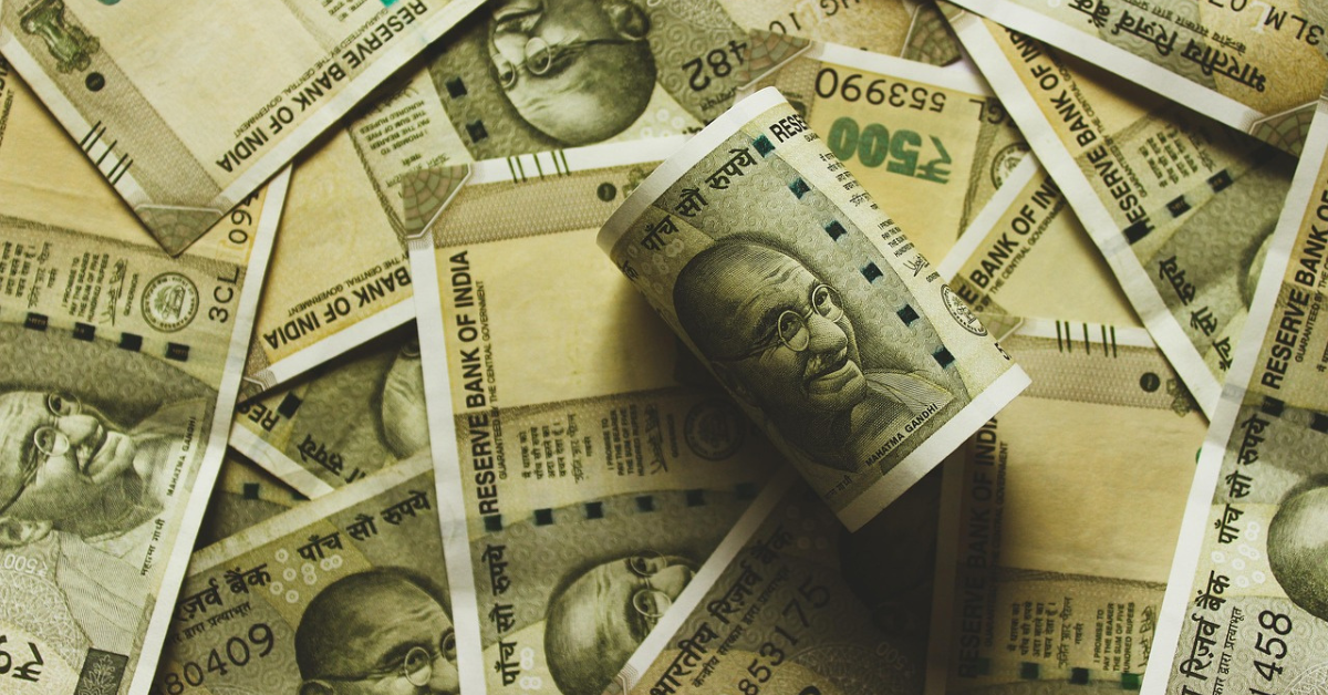 Indian rupee notes scattered with a rolled ₹500 bill in focus, representing currency depreciation